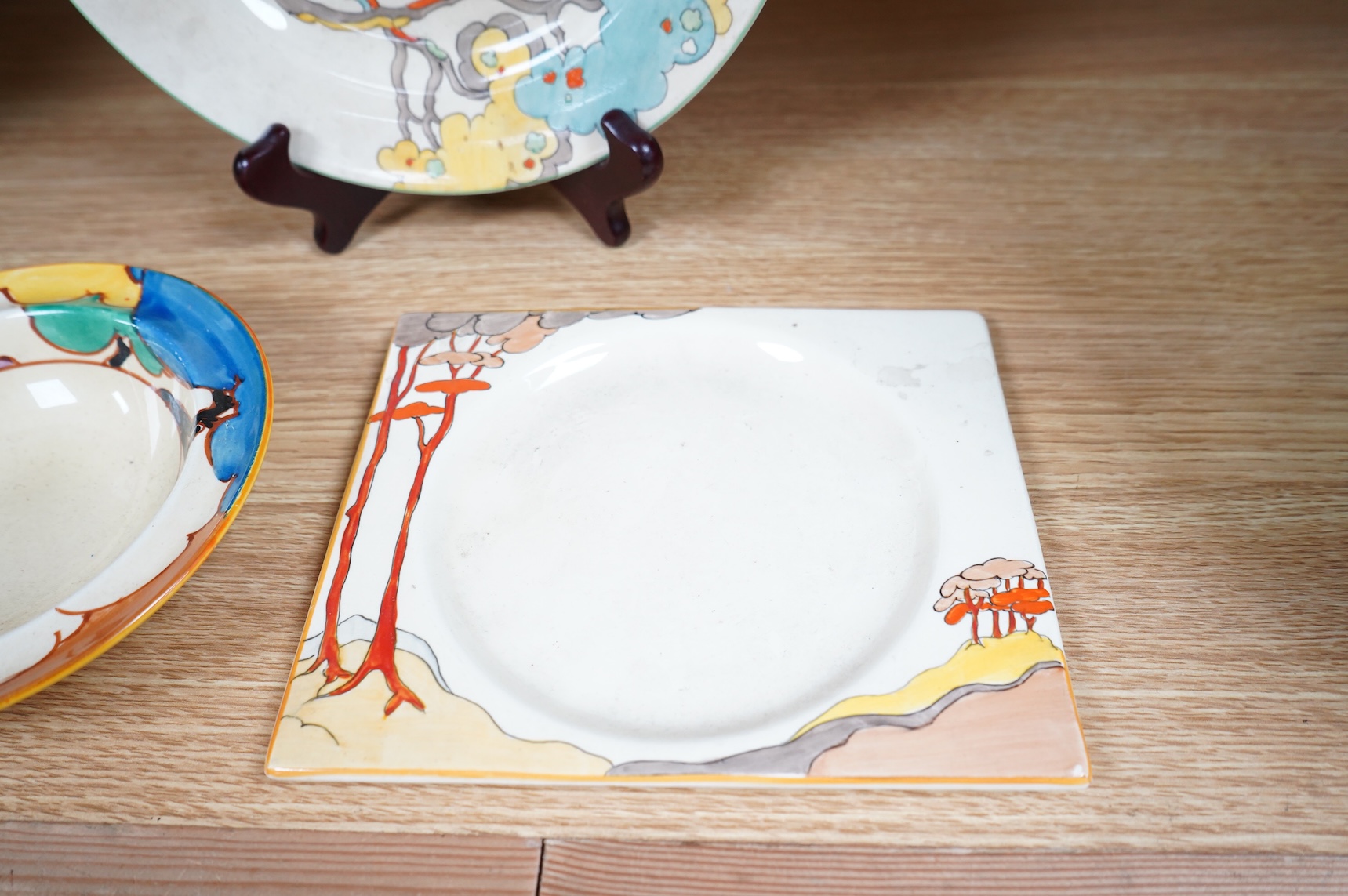 An early 20th century Clarice Cliff Bermuda pattern plate, Blue Autumn bowl and a Coral Firs Bizarre side plate, largest 23cm in diameter